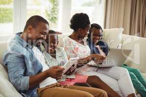 Parents and kids using laptop and digital tablet on sofa