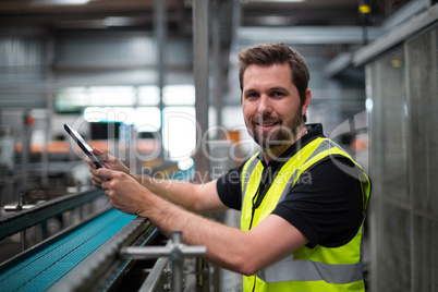 Portrait of smiling factory worker using a digital tablet