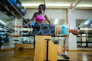 Trainer assisting woman with wunda chair in fitness studio