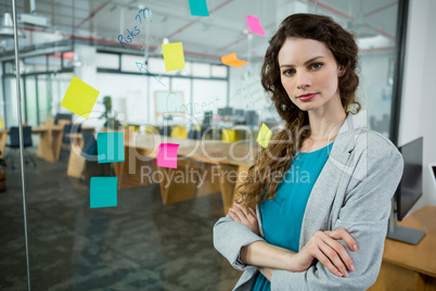 Confident female executive standing with arms crossed in creative office