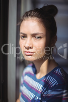 Worried schoolgirl standing in classroom