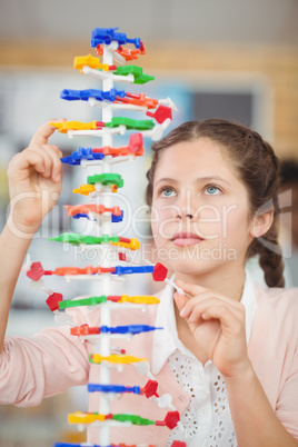 Schoolgirl experimenting molecule model in laboratory