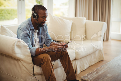 Man listening to music on mobile phone in living room