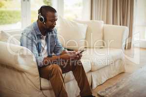 Man listening to music on mobile phone in living room