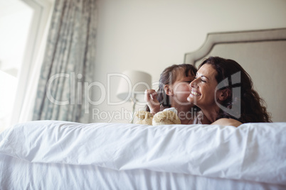 Daughter kissing her mother on cheek in bedroom