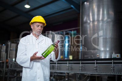 Factory worker examining a bottle in factory