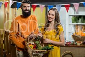 Man and woman holding a basket of vegetables at the grocery store