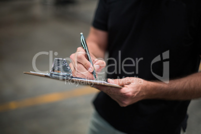 Factory staff writing on clipboard in factory
