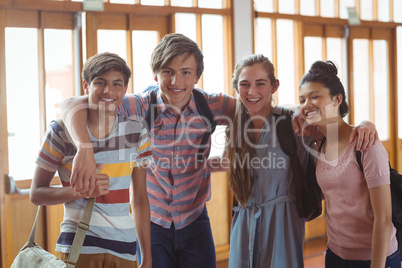 Portrait of happy students standing with arms around in campus