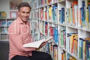 Portrait of school teacher holding book in library