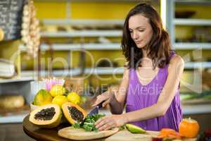 Shop assistant chopping leaf vegetable at counter