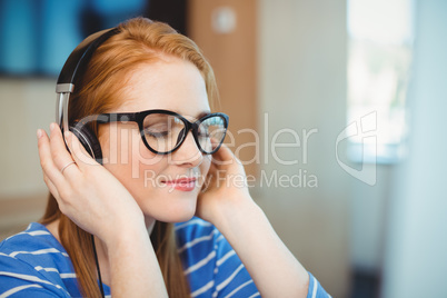 Female graphic designer listening music on headphones