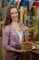 Smiling woman holding a basket of tomatoes in the grocery store