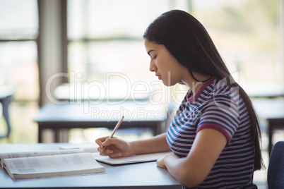 Attentive schoolgirl studying in classroom