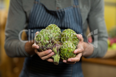 Vendor holding custard apples at the grocery store
