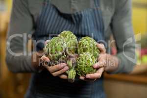 Vendor holding custard apples at the grocery store