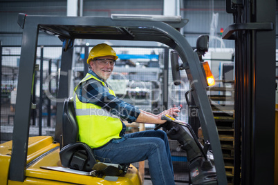 Portrait of smiling factory worker driving forklift