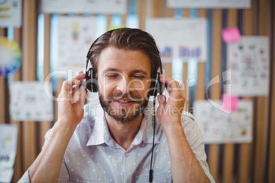 Close-up of male graphic designer listening music on headphone