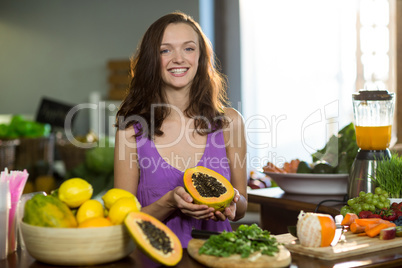 Smiling shop assistant holding half papaya at the counter