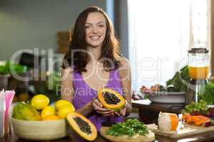 Smiling shop assistant holding half papaya at the counter