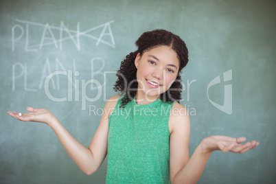 Portrait of schoolgirl gesturing while pretending to be a teacher in classroom