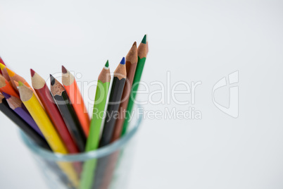 Colored pencils kept in glass on white background