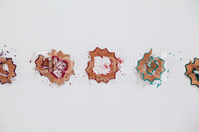 Red, blue and green colored pencil shavings on white background