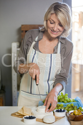 Smiling female staff slicing cheese at counter