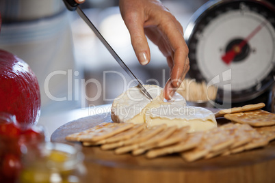 Hand of female staff slicing cheese at counter