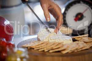 Hand of female staff slicing cheese at counter