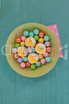 Colorful chocolates and cupcakes in bowl