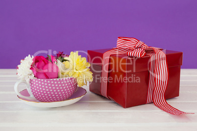 Gift box and fresh flowers on wooden surface