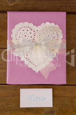 Gift box with mom text on card against wooden background