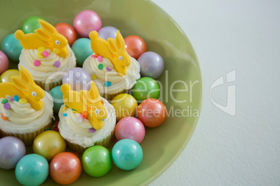 Colorful chocolate Easter eggs with cup cakes in bowl