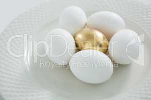Golden Easter egg with white eggs in plate