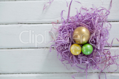 Golden Easter egg with two painted eggs in nest