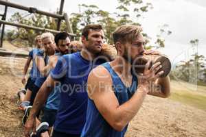 People holding a heavy wooden log during boot camp