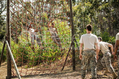 Military soldiers climbing rope during obstacle course