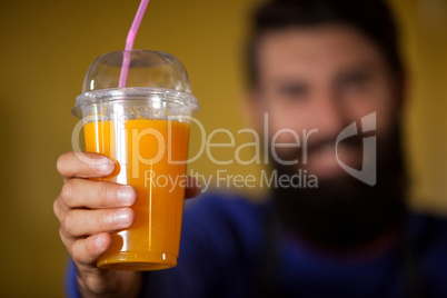 Male staff holding orange juice glass at organic section