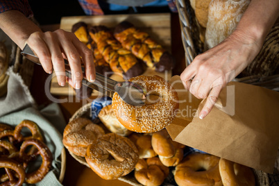 Mid section of staff packing doughnut in paper bag at counter