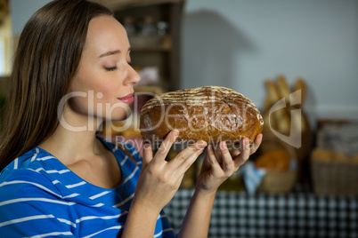 Smiling woman smelling a round loaf of bread at counter