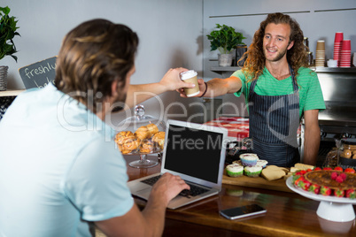 Customer receiving a coffee from staff at counter