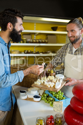 Staff showing a sample of cheese to customer at counter