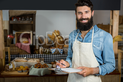 Salesman writing on clipboard at counter in grocery shop