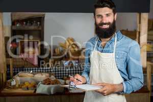 Salesman writing on clipboard at counter in grocery shop