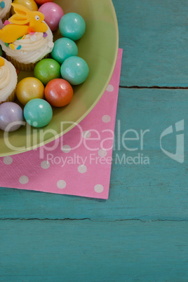 Colorful chocolates and cupcakes in bowl