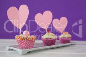 Close-up of three delicious cupcakes with heart shape cards in tray
