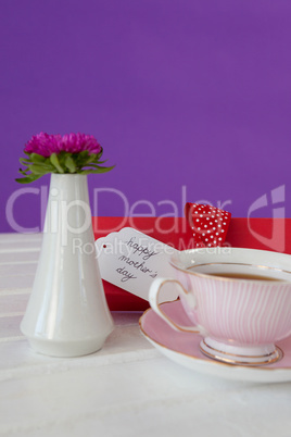 Black tea, flower vase and happy mothers day card on wooden surface