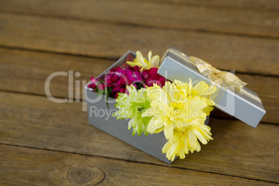 Gift box with flowers on wooden surface