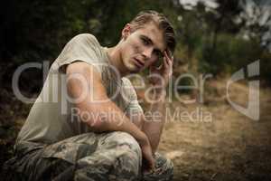 Tired soldier with hand on head sitting in boot camp